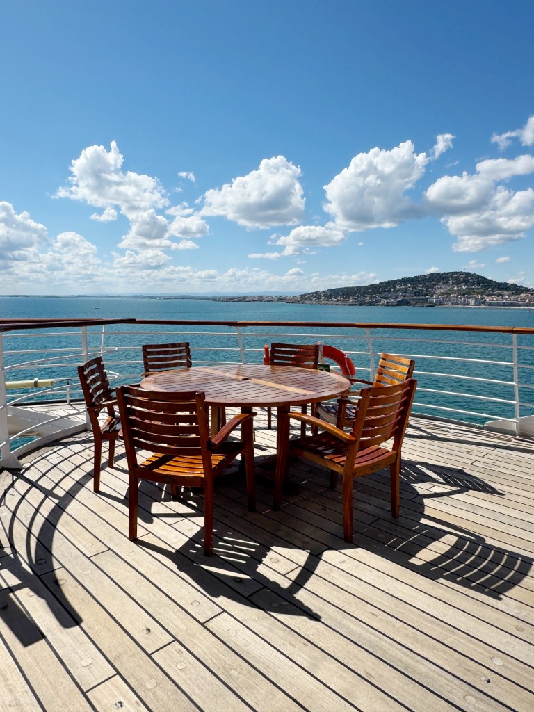 A dark wood outside dining table on an open deck of Crystal Serenity