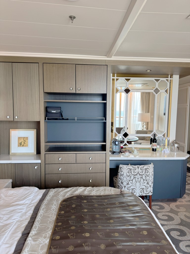 A bed, with a luggage mat on it, with storage space and a deck and chair behind.