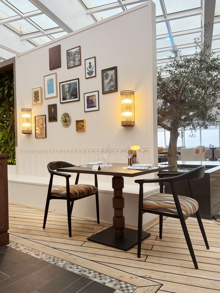 A table in beefbar, with a wall with lots of photographs on and a tree.