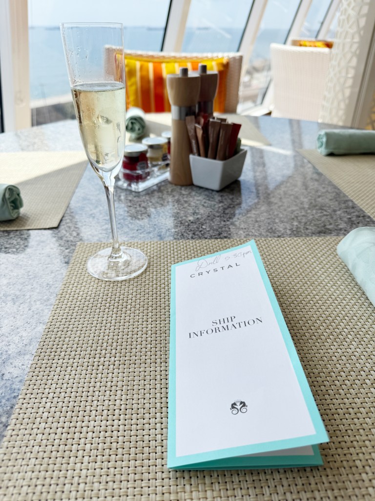 A glass of champagne on a table with a Ship Information leaflet
