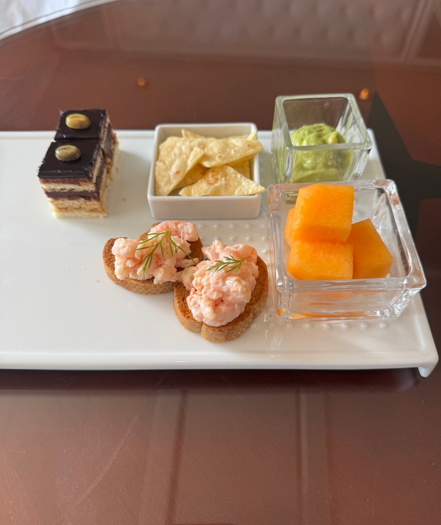 A selection of canapes, prawns, melon, chips and dips and chocolate cake.