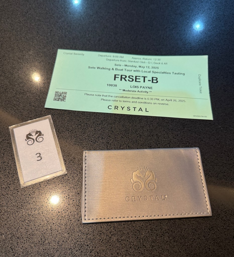 A Shore excursion ticket and a Crystal cruise card wallet on a table next to each other.