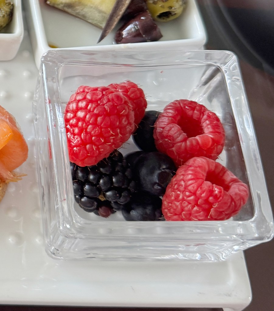 Raspberries and blackberries in. small glass bowl.