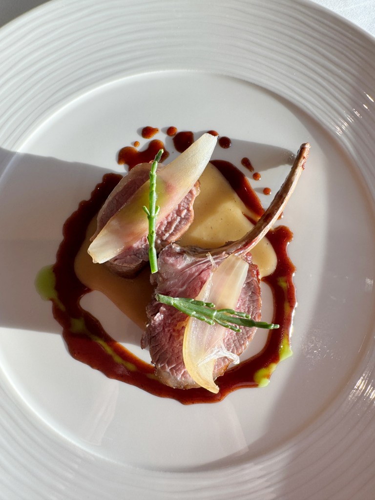 A main lamb dish with potatoes and green garnish.