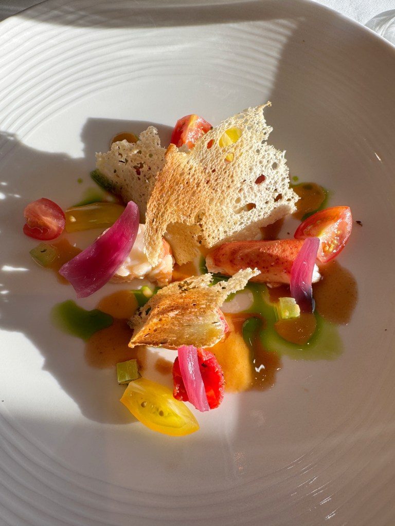 A very colourful lobster dish with salad, with reds, orange and yellow colours.