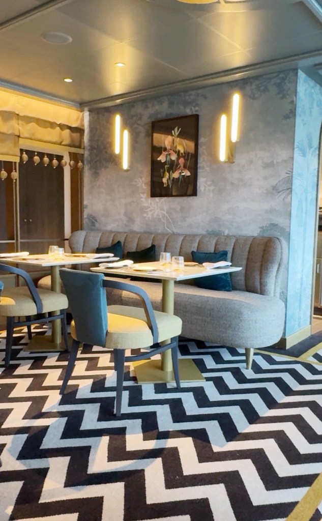 Interior view of a modern restaurant with stylish seating, a decorative wall painting, and a chevron patterned rug.