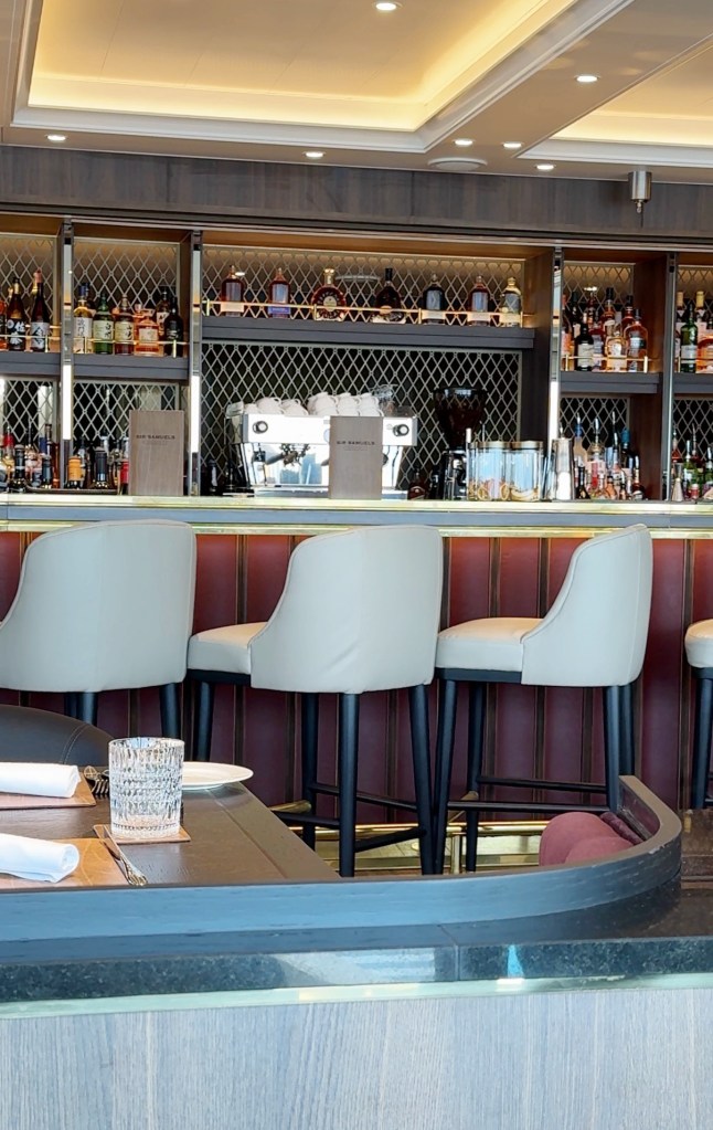 A bar with three white bar stools.